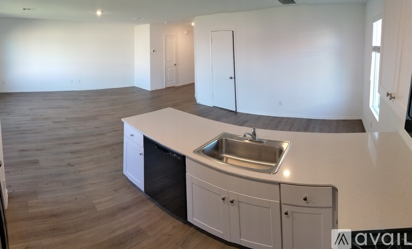 A kitchen with a sink and cabinets in a room with wooden floors.