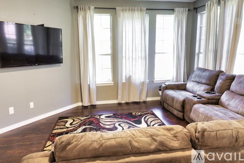 A living room with a large couch and a flat screen TV mounted on the wall.