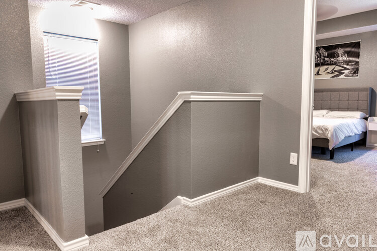 A bedroom with a bed, a window with blinds, and a staircase.