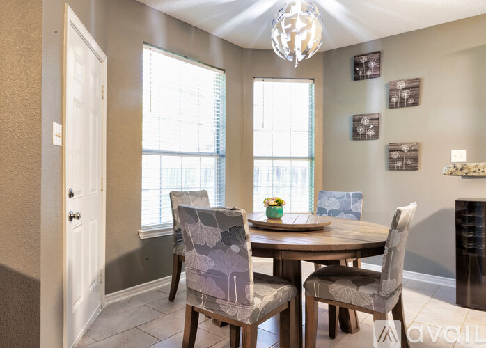 A dining room with a table set for two and a chandelier hanging from the ceiling.
