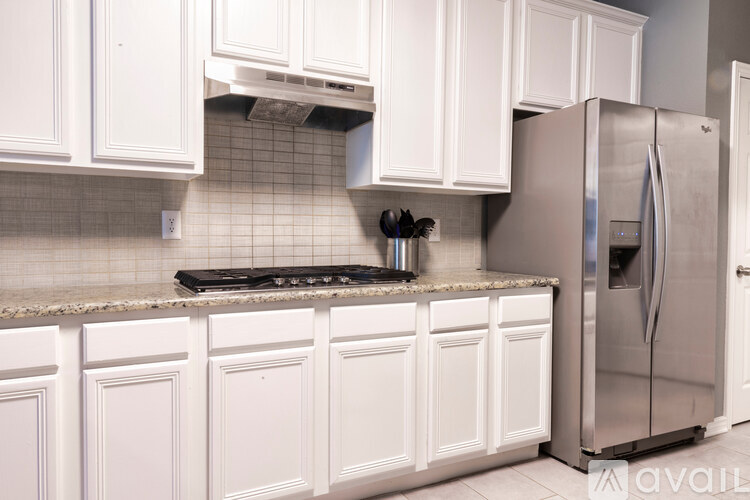 A kitchen with white cabinets and a stainless steel refrigerator.