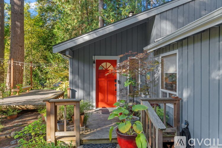 A house with a red door is surrounded by greenery.