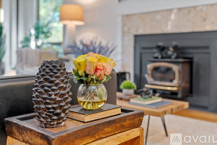 A pineapple, a vase with flowers, and a book are on a wooden table.
