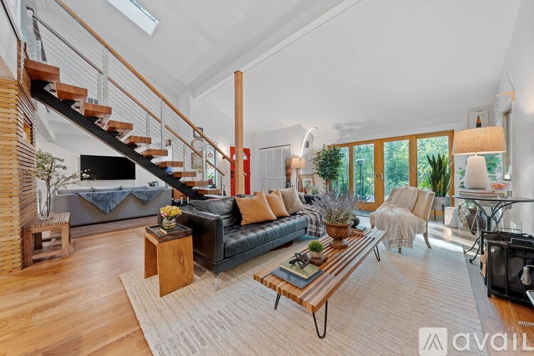 A living room with a black leather couch, a wooden coffee table, and a staircase with a wooden railing.