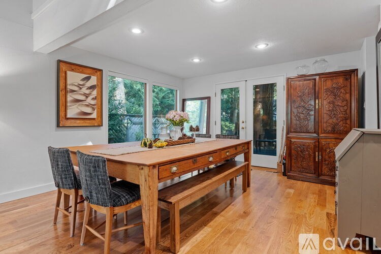 A wooden dining table with chairs and a vase of flowers on top.