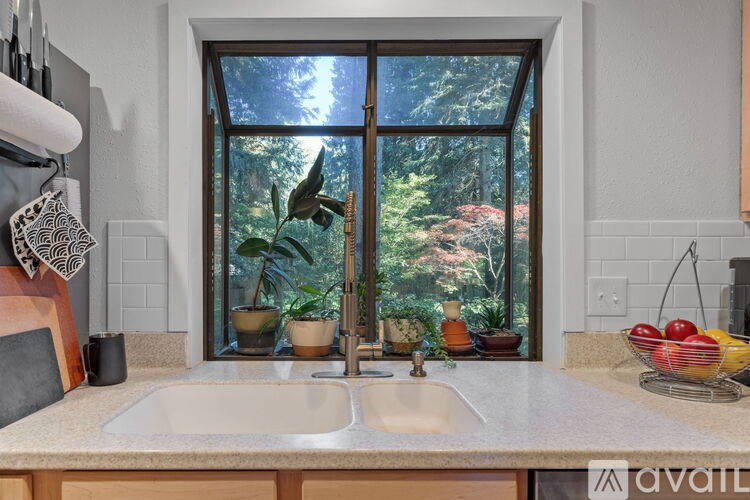 A kitchen with a sink and a window overlooking a garden.