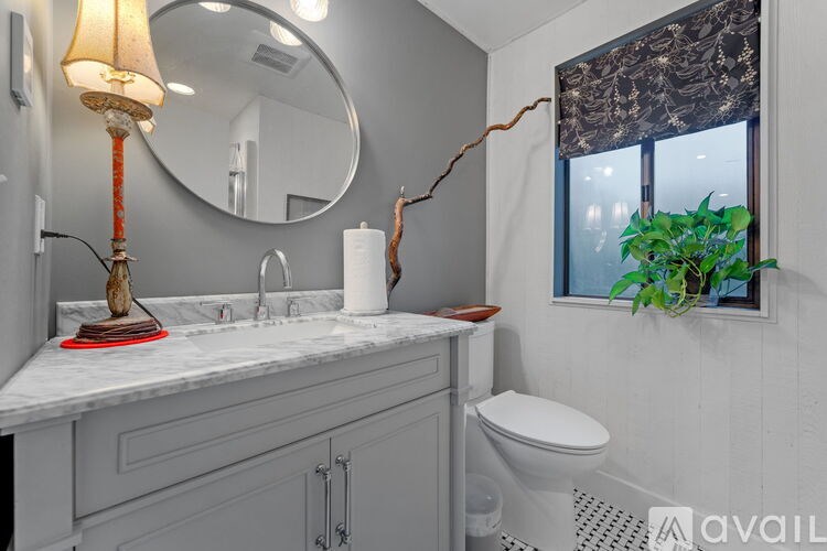 A bathroom with a marble countertop and a round mirror.