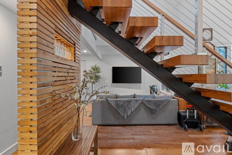 A living room with a grey couch and a wooden staircase.