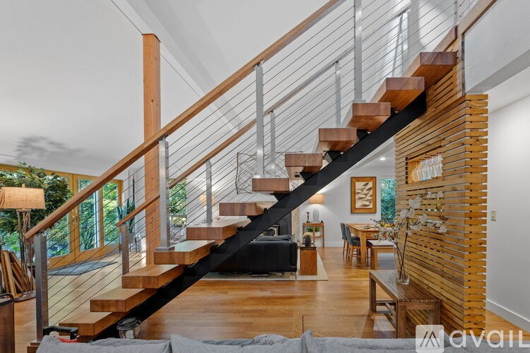 A wooden staircase with a metal railing leads to a living room.