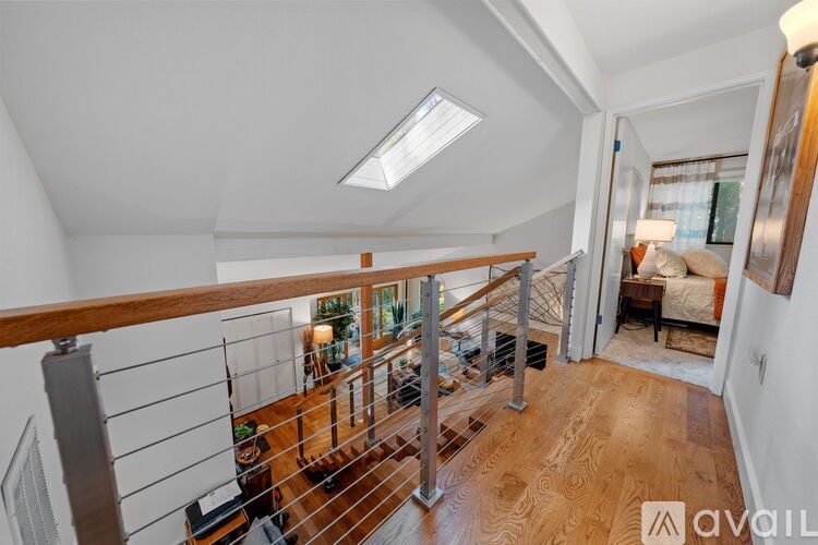 A well-lit, spacious room with a skylight and a wooden staircase leading to the upper floor.