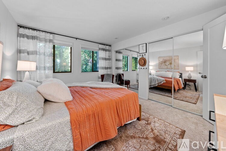 A bedroom with a bed covered in an orange and grey bedspread.