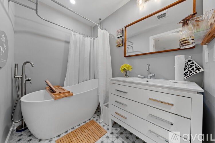 A white bathroom with a tub, sink, and mirror.