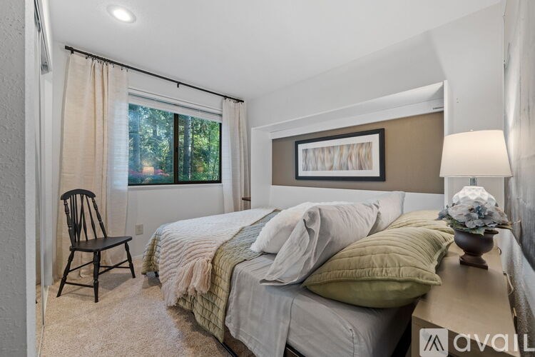A bedroom with a bed, chair, and a painting on the wall.