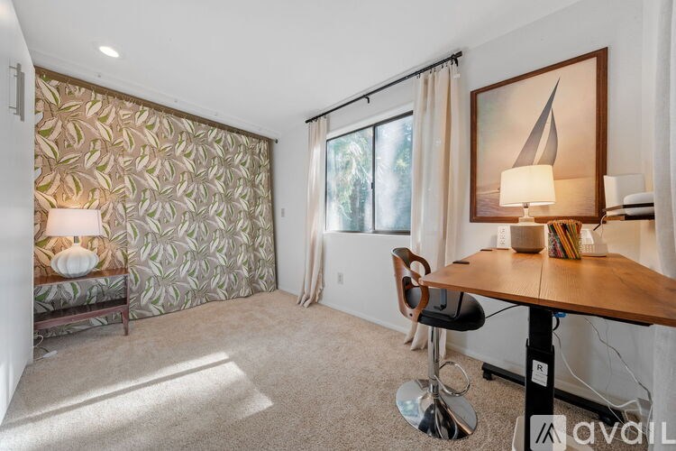 A room with a desk, chair, and a painting on the wall.