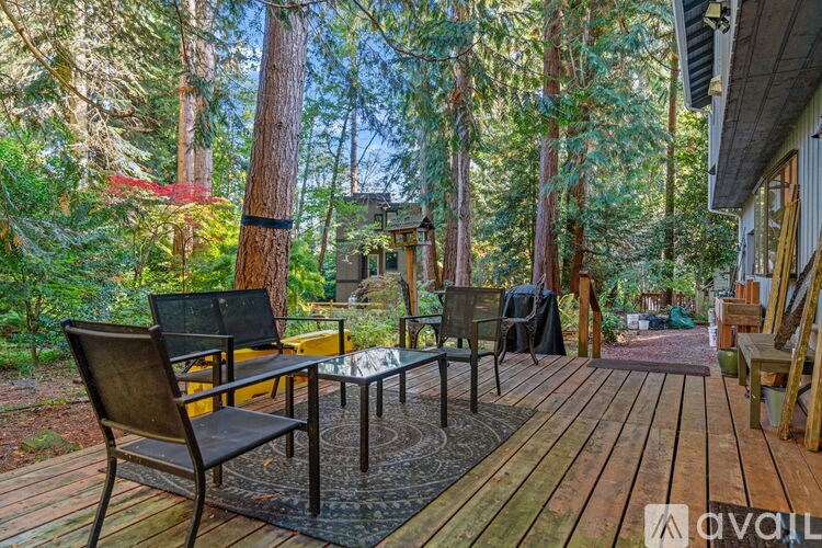 A wooden deck with a table and chairs overlooking a forest.