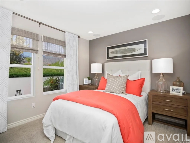 A bedroom with a large bed and a window overlooking a green landscape.