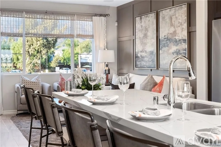 A kitchen with a table set for two with a view of the street outside.