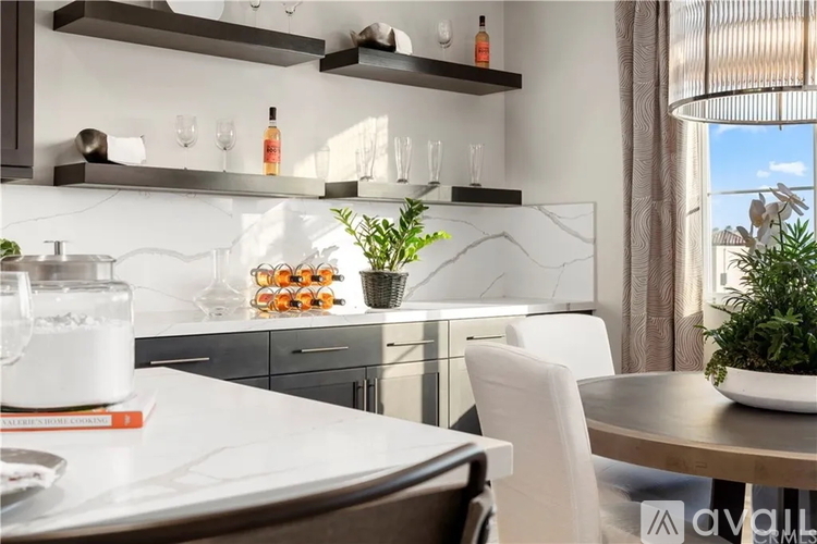 A modern kitchen with a white countertop and a dining table set for two.