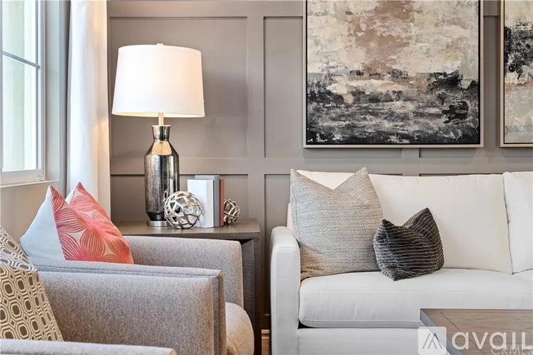 A living room with a grey couch, a white couch, and a grey side table with a lamp and decorative items.
