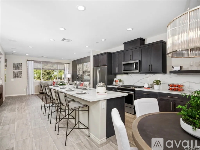 A modern kitchen with black cabinets and a white island.