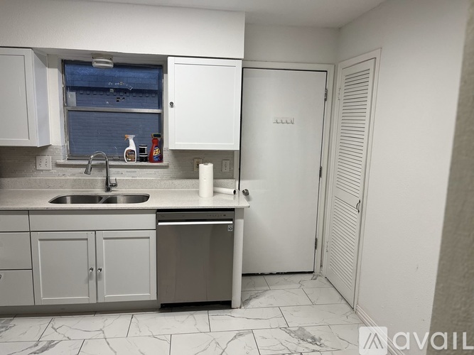 A kitchen with a sink, dishwasher, and cabinets.