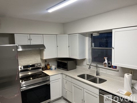 A kitchen with white cabinets and a stainless steel refrigerator.