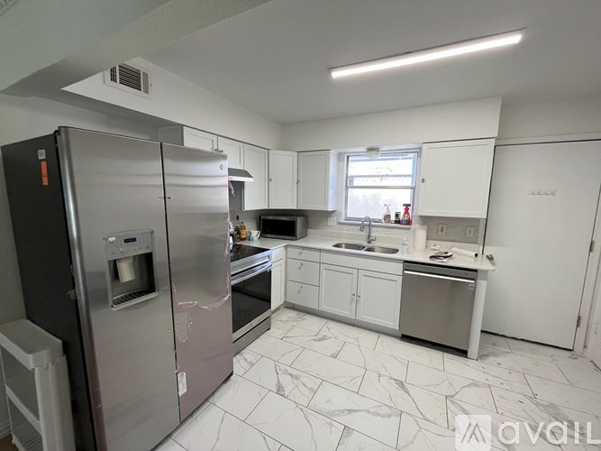 A kitchen with a refrigerator, oven, sink, and cabinets.