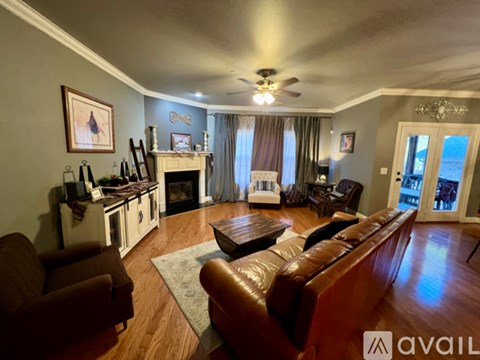 A living room with a brown leather couch and a fireplace.