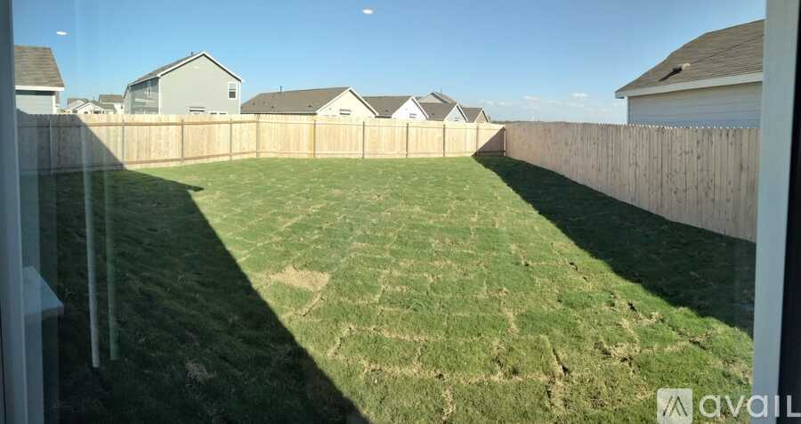 A backyard with a wooden fence and a grassy area.