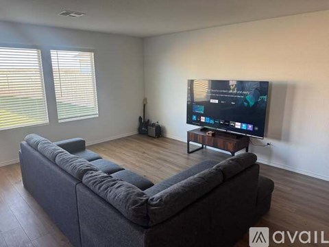 A modern living room with a grey sofa and a flat screen TV mounted on the wall.