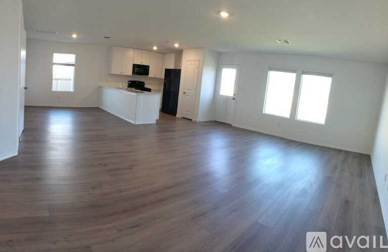 A spacious room with wooden flooring and white walls.
