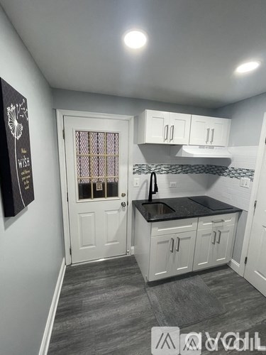 A kitchen with white cabinets and a black countertop.