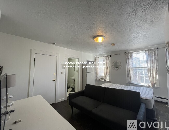 A living room with a black couch and a white dining table.