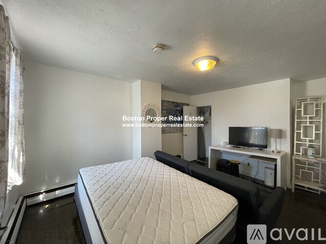 A bedroom with a large bed and a television in the corner.