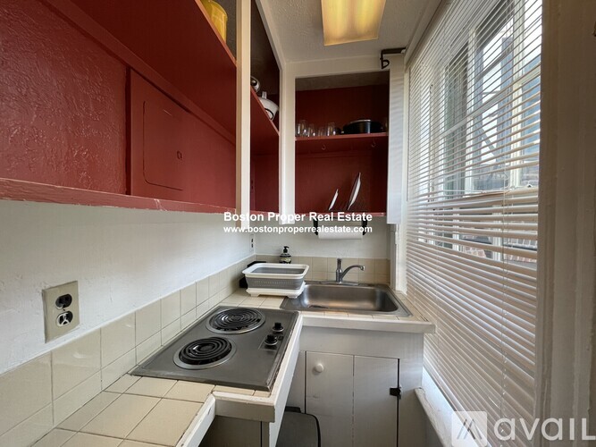 A kitchen with red cabinets and a stove top oven.