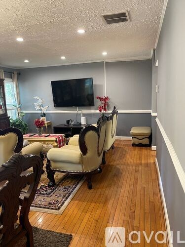 A living room with a television, chairs, and a rug.