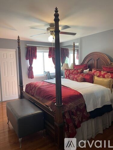 A bedroom with a four poster bed and a bench in front of it.