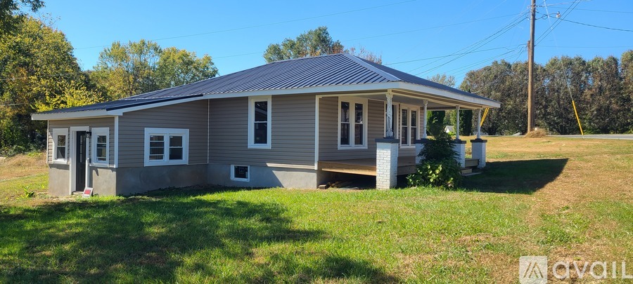 A house with a grey roof and a porch is for sale.