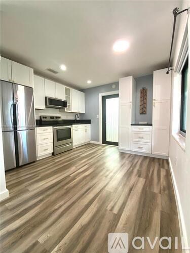 A modern kitchen with wooden floors and stainless steel appliances.