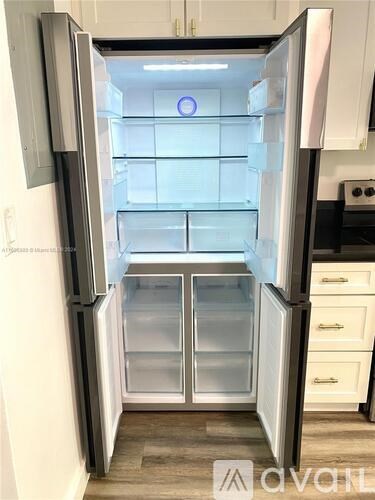 A white refrigerator with its door open and empty.