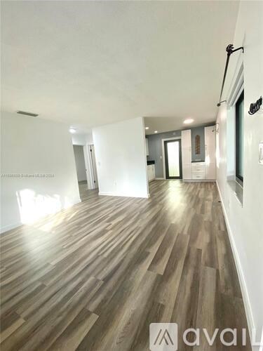 A long hallway with wood floors and white walls.