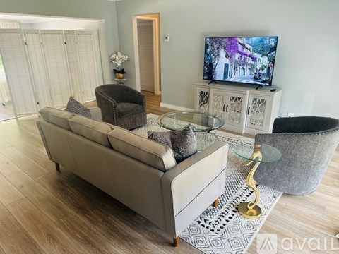 A living room with a grey couch, a glass table, and a television on a cabinet.