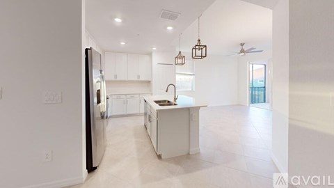A kitchen with white cabinets and a black fridge is available for rent.