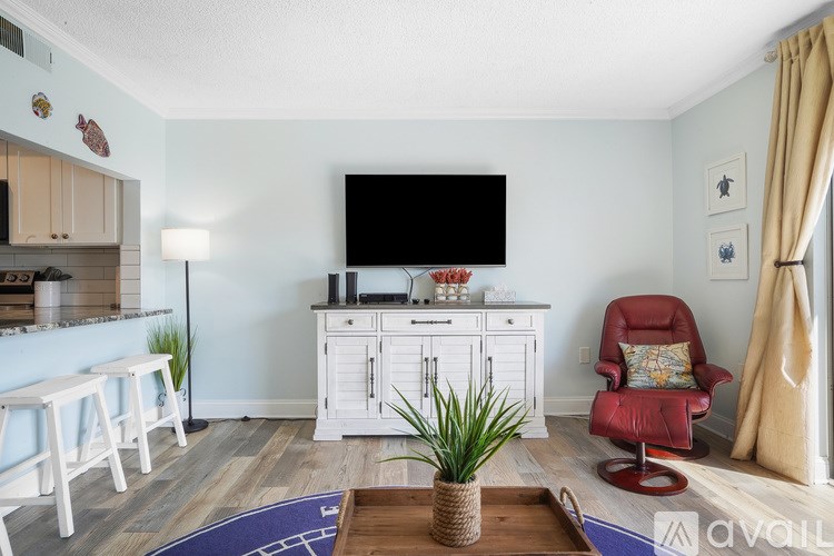 A living room with a red chair and a television on a white cabinet.