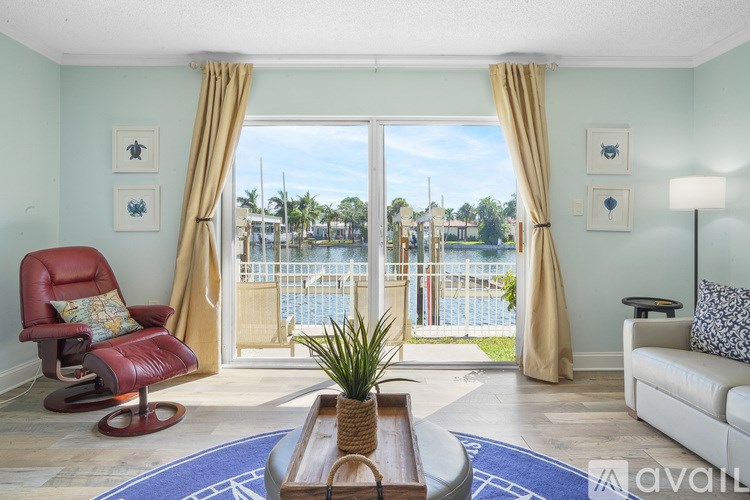A living room with a red chair and a view of a pool through the sliding glass doors.