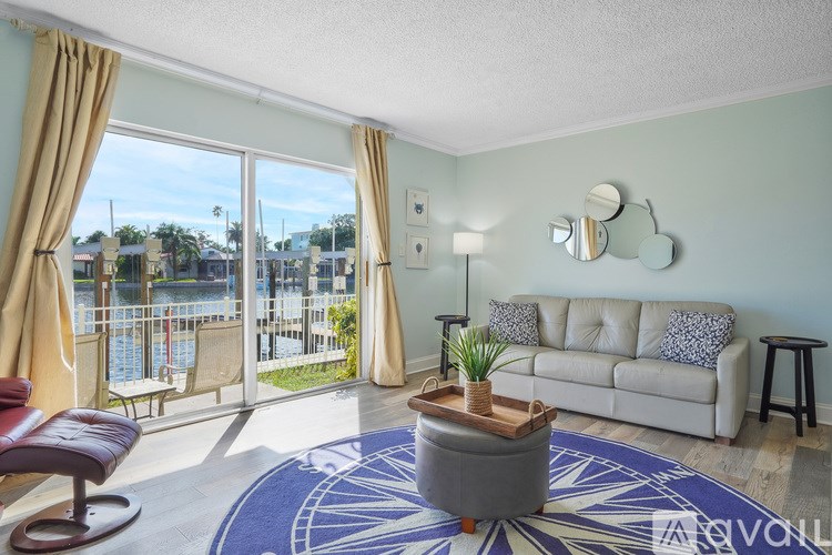 A living room with a couch, chair, and a view of a pool through the window.