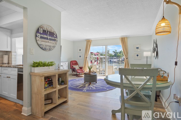 A living room with a clock on the wall and a dining table with chairs.