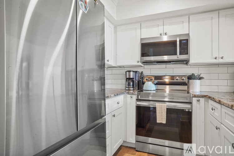 A modern kitchen with stainless steel appliances and white cabinets.