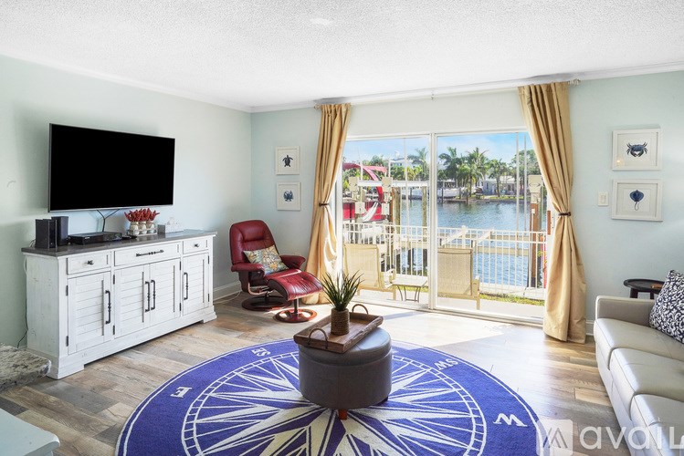 A living room with a television, a red chair, and a view of a pool.