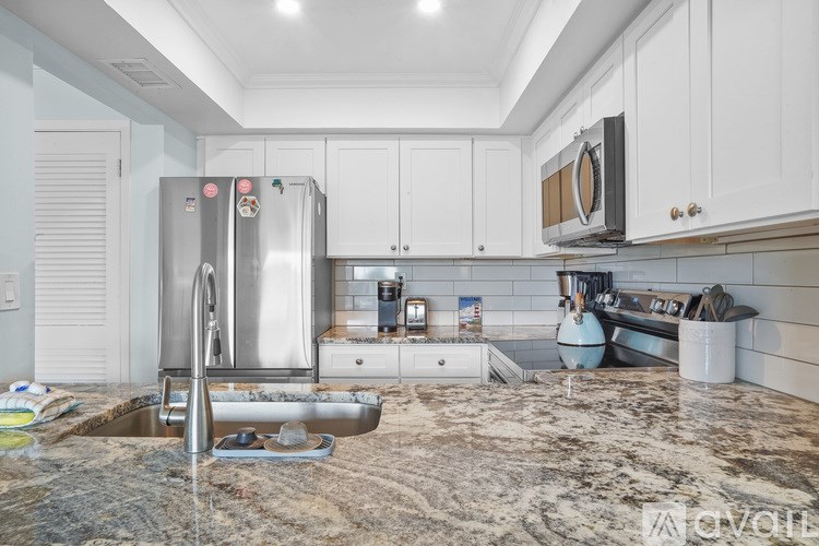 A kitchen under renovation with a sink, refrigerator, and cabinets.